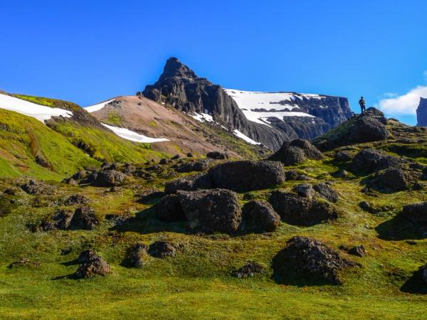 una persona está de pie en la cima de una colina cubierta de hierba en las montañas.