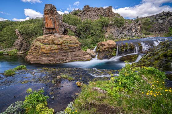 Lava formations next to a river and a small waterfall