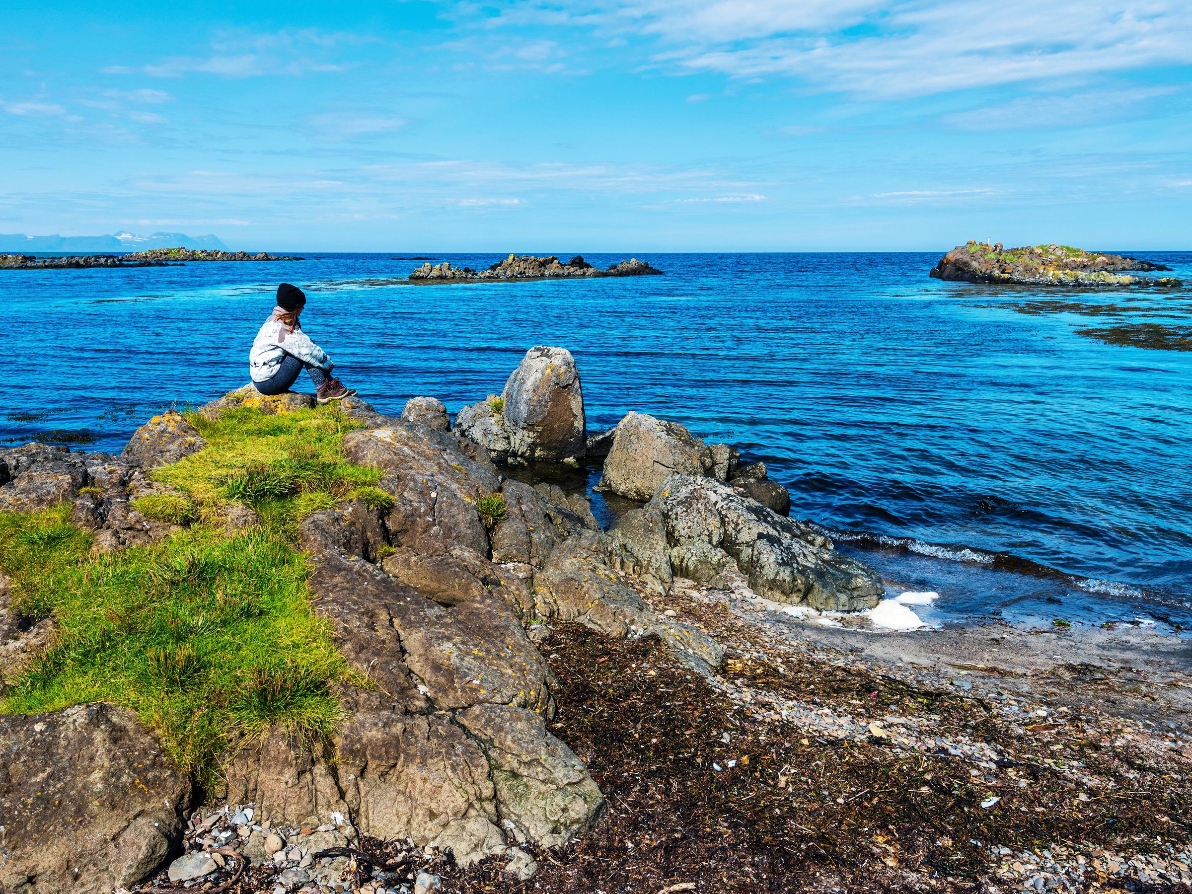 Persona sentada en una roca junto al mar en Islandia