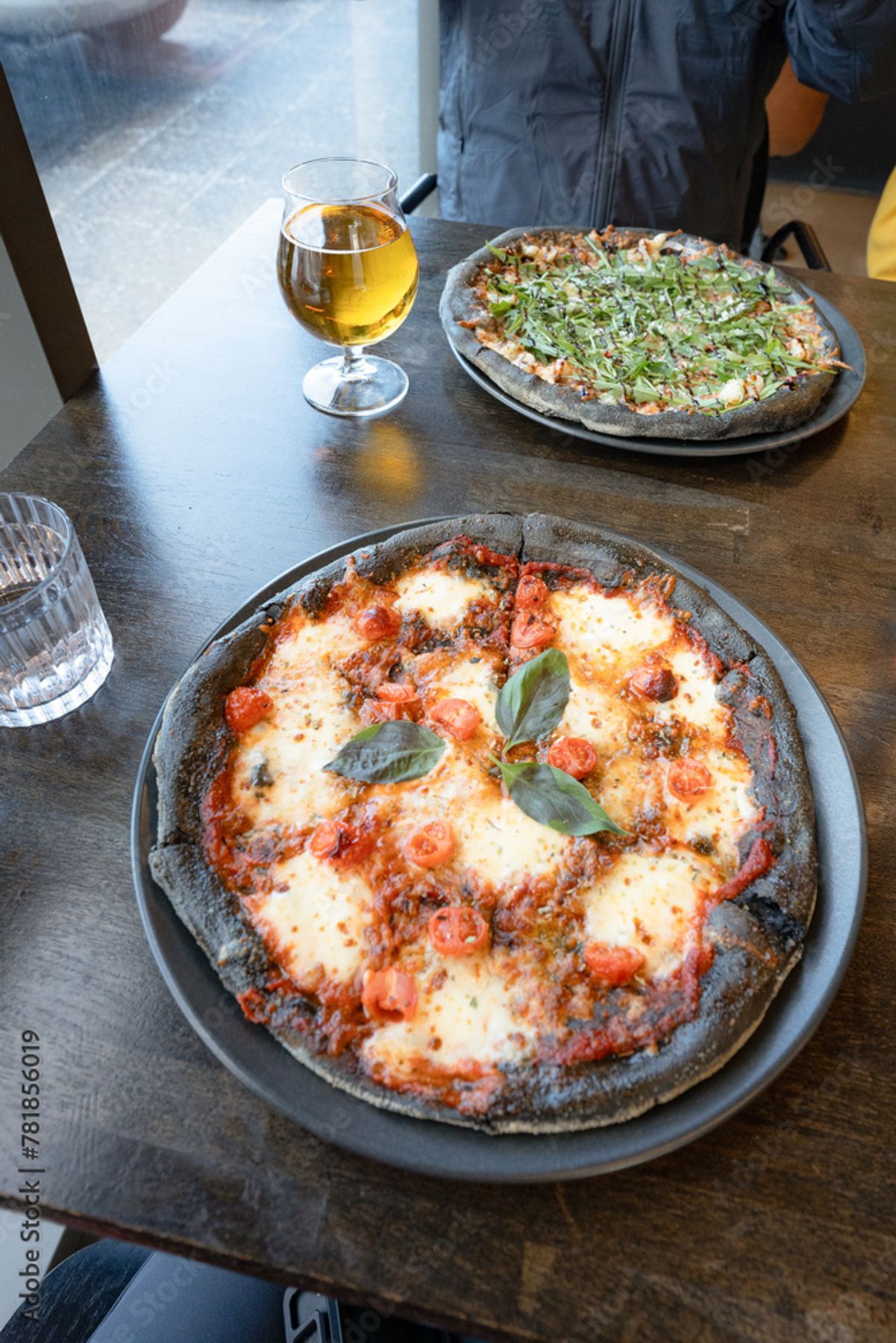 una mesa de madera con dos pizzas y una copa de cerveza