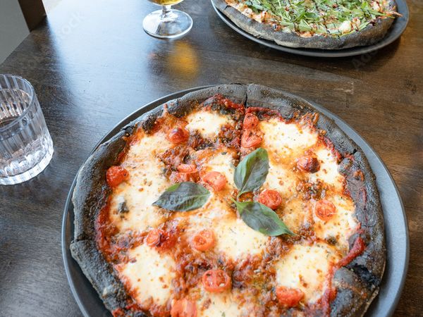 a wooden table with two pizzas and a beer