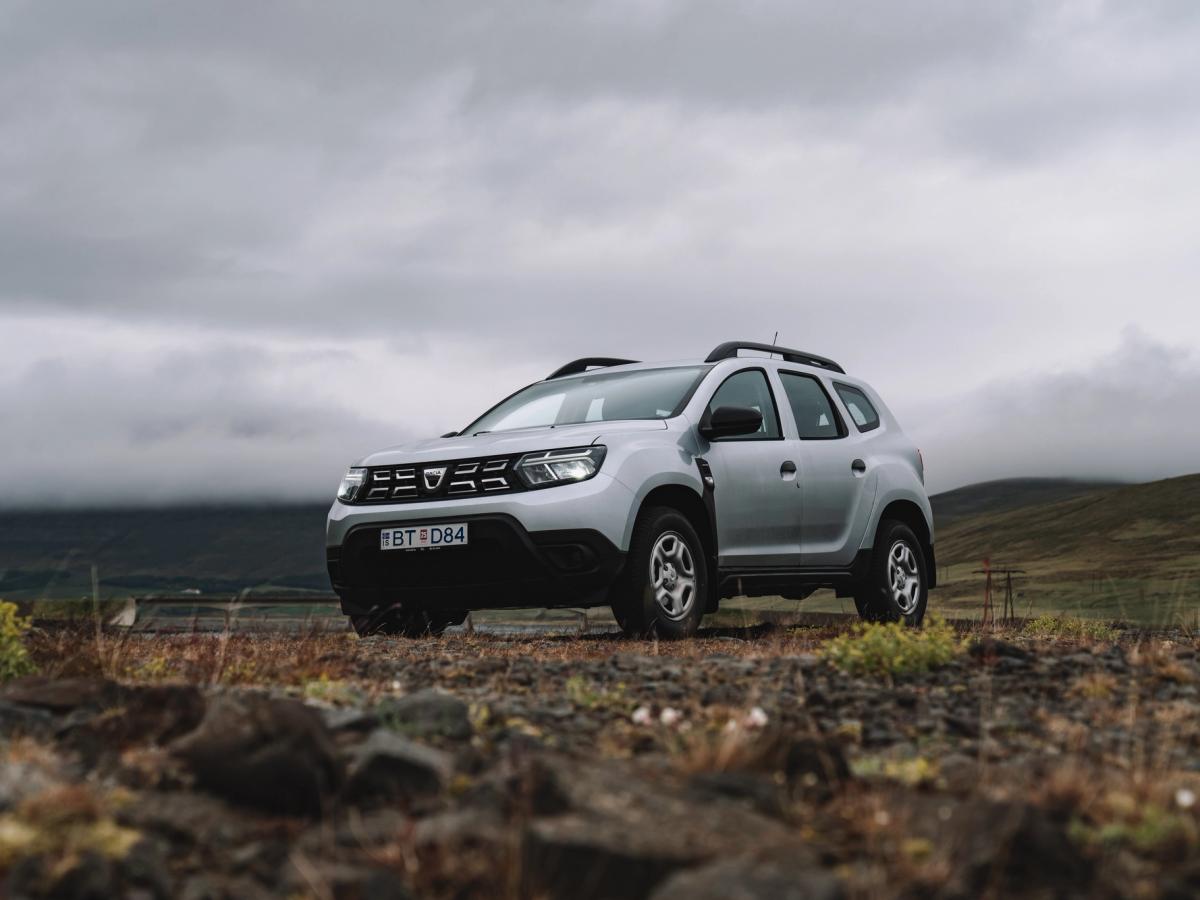 Mirador Highland del Dacia Duster SUV Dacia Duster de alquiler en Islandia, aparcado sobre un terreno rocoso con vistas a un amplio paisaje de las tierras altas