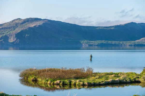 un hombre pescando a pie dentro de un gran lago
