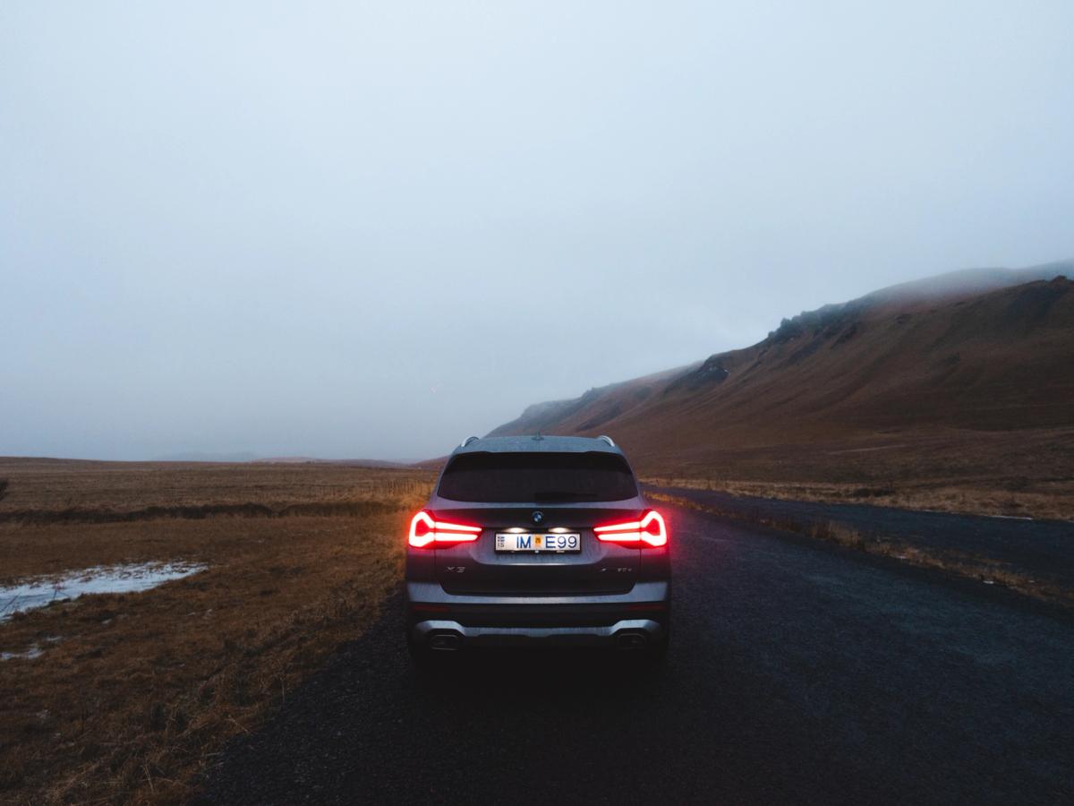 Vue arrière sombre du X3 BMW X3 rear view with illuminated taillights on open highland landscape road