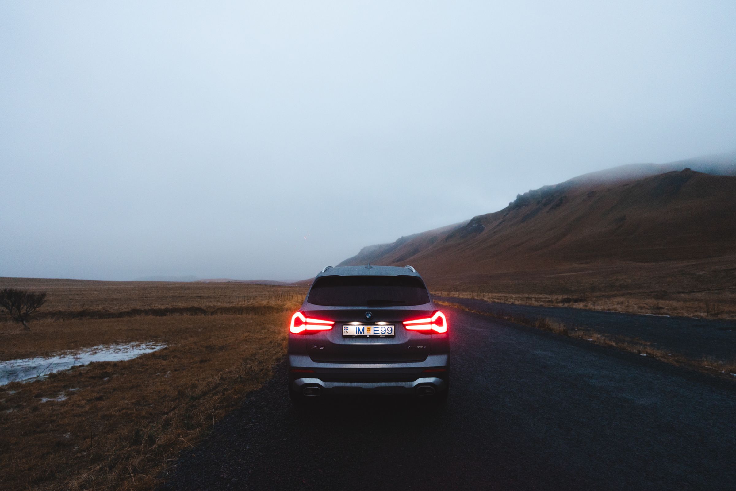 Vue arrière sombre du X3 BMW X3 rear view with illuminated taillights on open highland landscape road
