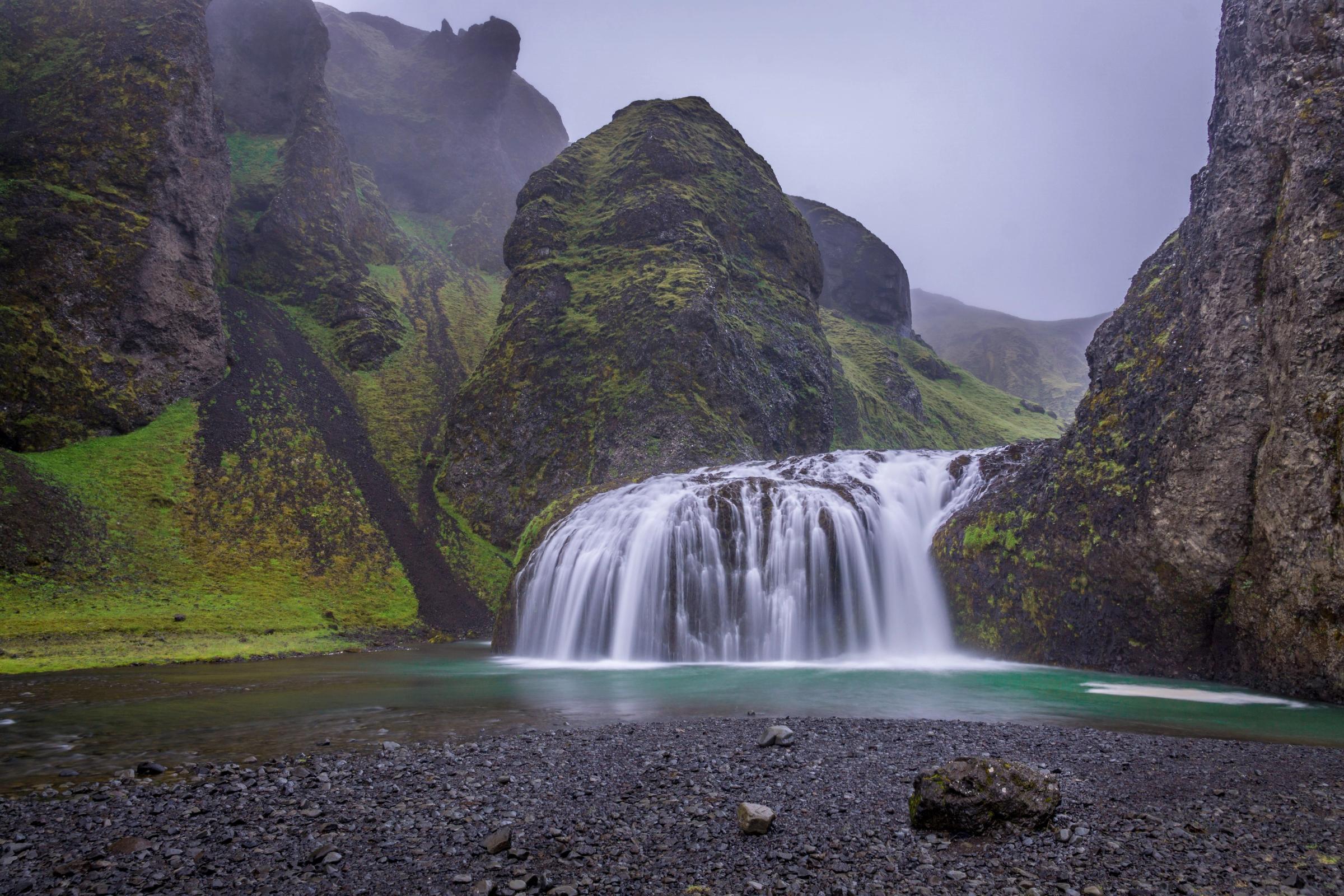 ancha cascada que cae sobre una laguna