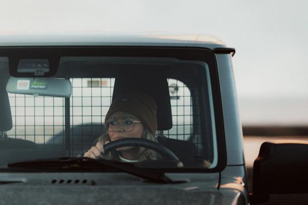 Embracing the open road: A woman takes the wheel of a 4x4 rental car A woman confidently driving a 4x4 rental car on an open road
