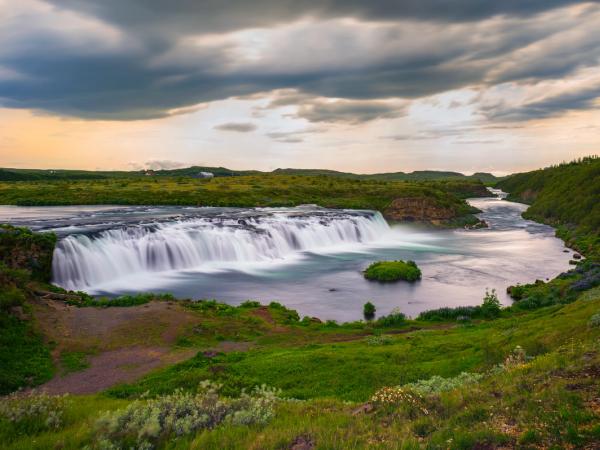 there is a waterfall in the middle of a river in the middle of a field .