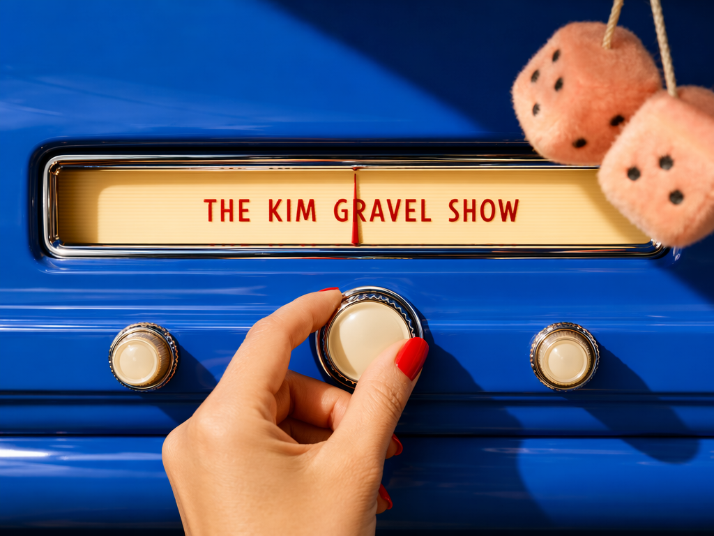 A hand tuning a retro radio dial on a blue dashboard, fuzzy peach dice hanging beside it