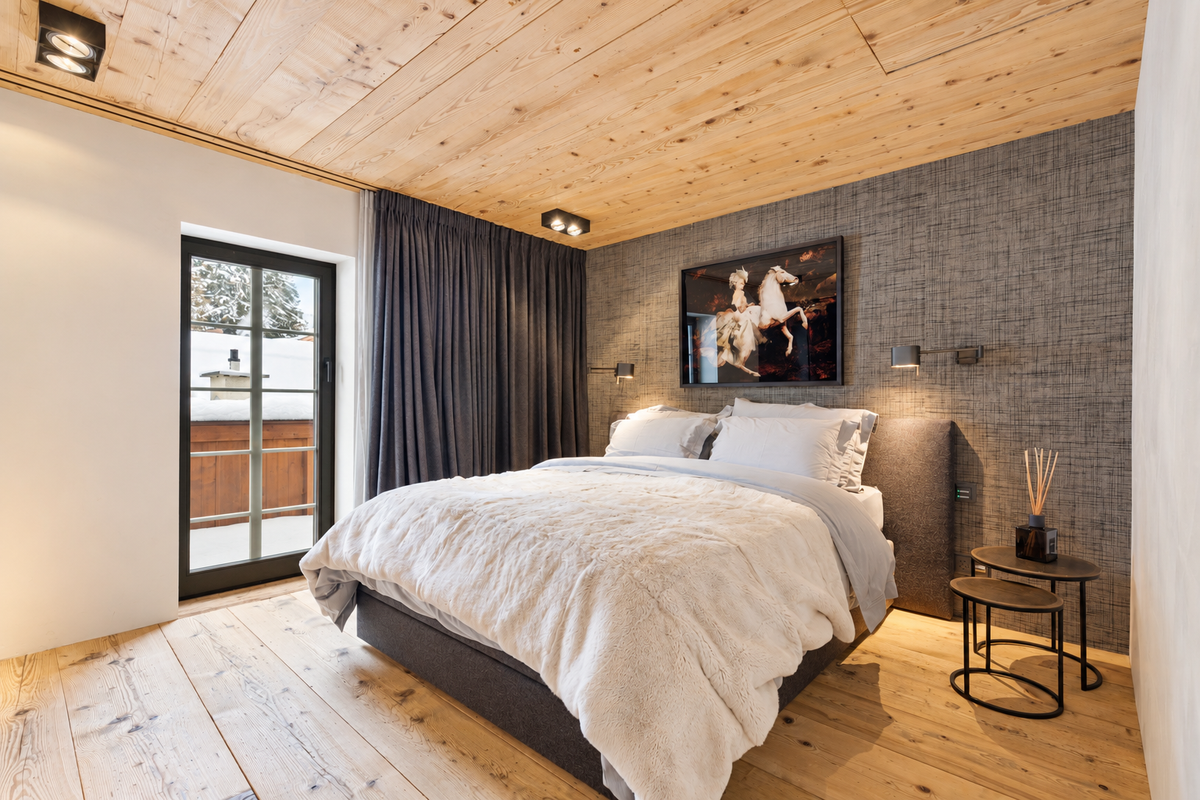 Bedroom under a timber ceiling, with a door onto the balcony