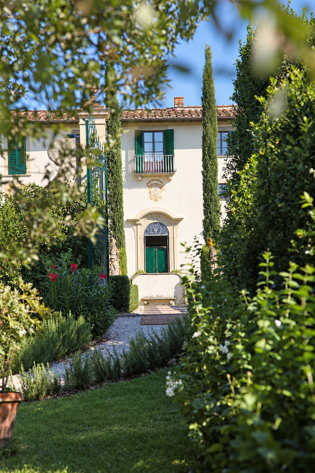 The villa glimpsed through the garden gate among roses and cypresses