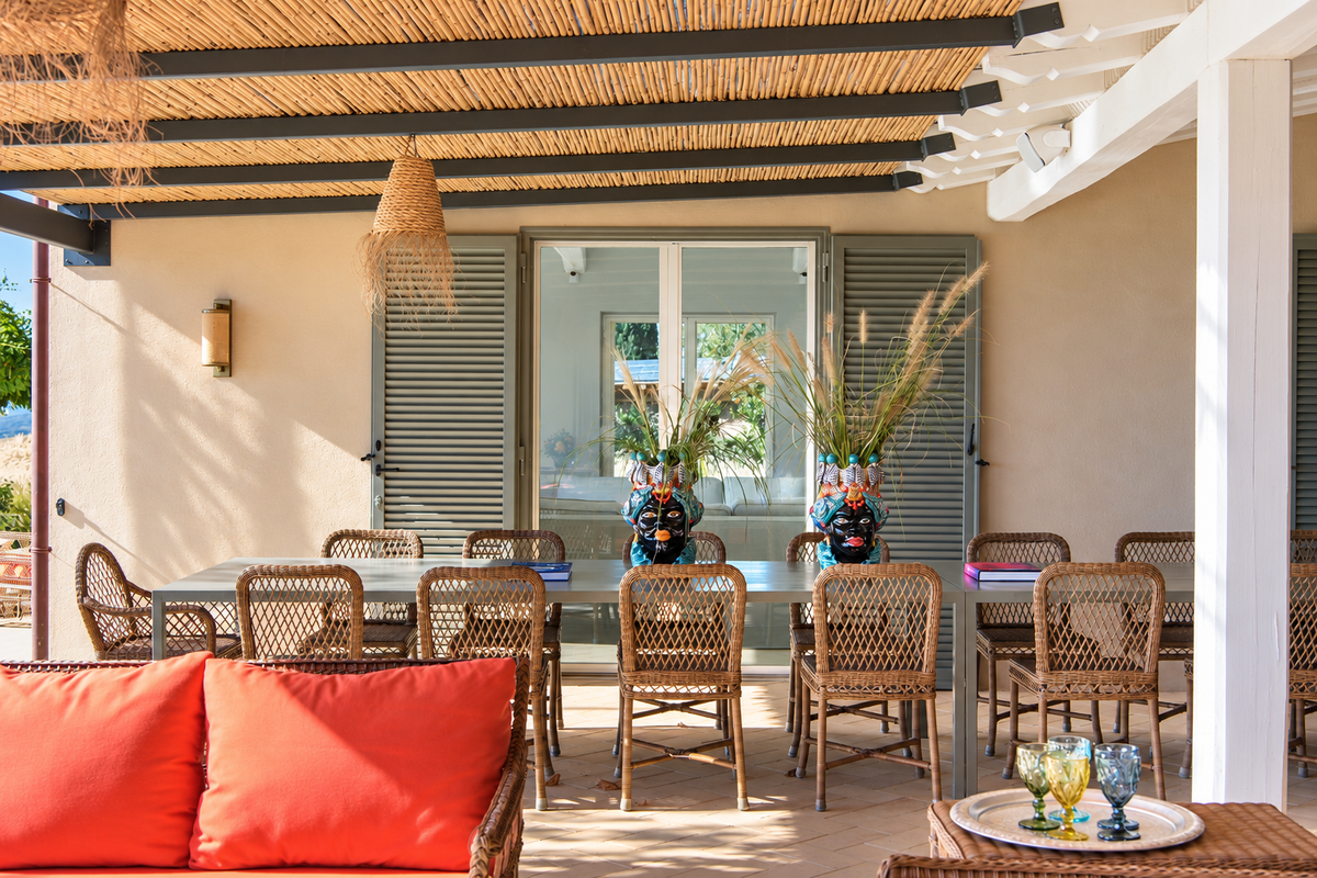 Long dining table with wicker chairs on the veranda
