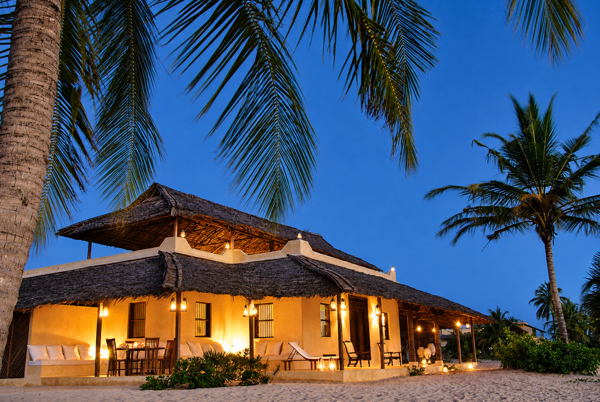 Beachfront villa lit at night among palms
