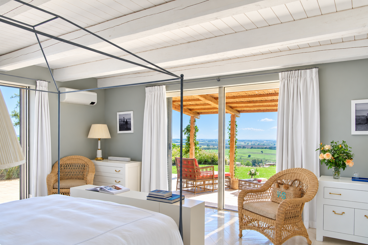 Bedroom with an iron canopy bed and a terrace onto the countryside