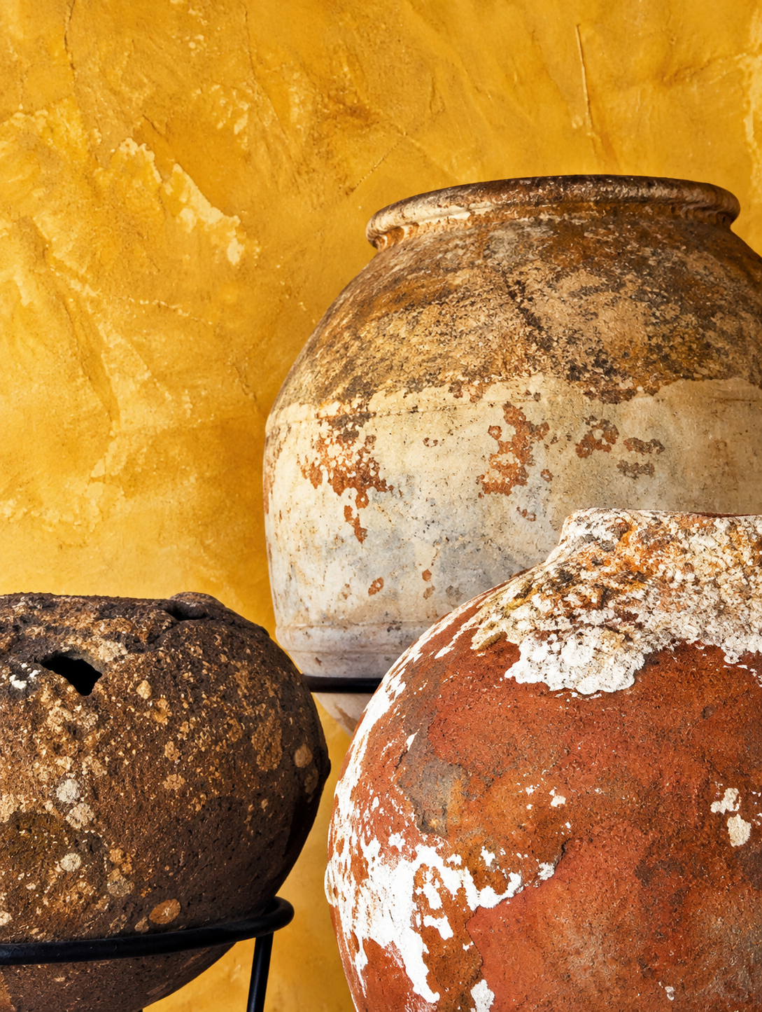 Old clay pots against an ochre wall