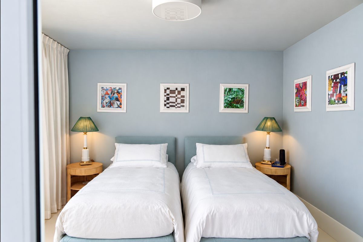 Twin bedroom in pale blue with colourful prints
