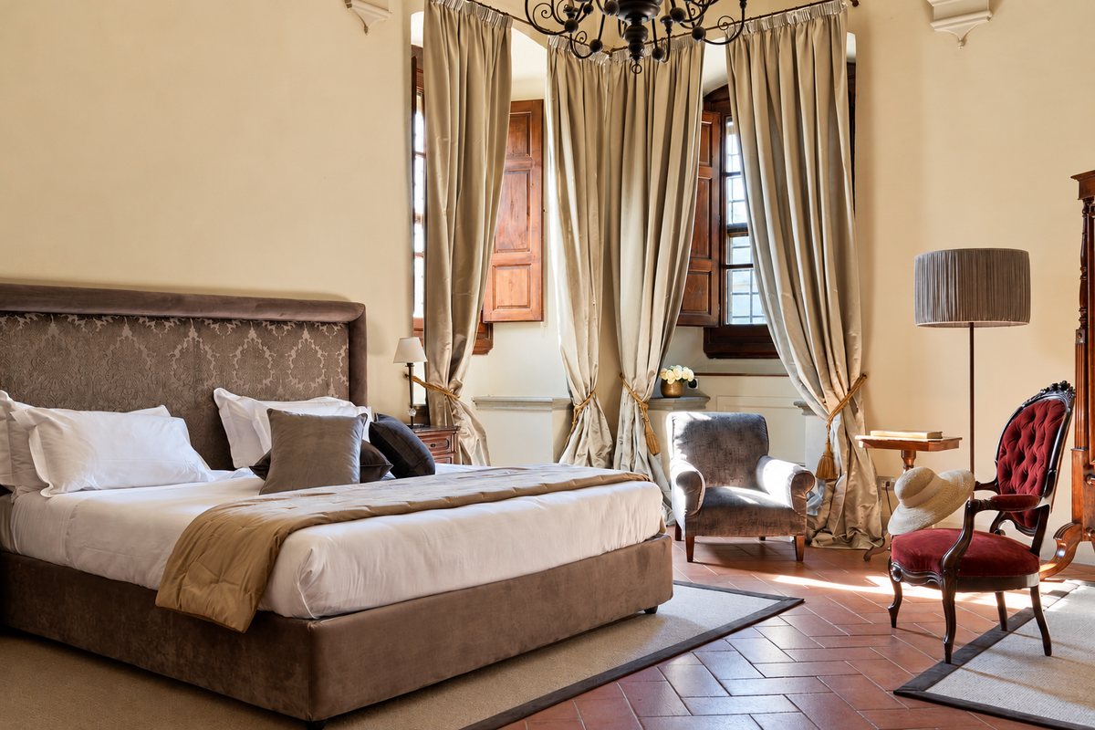 Vespucci junior suite with a velvet armchair and tall curtains