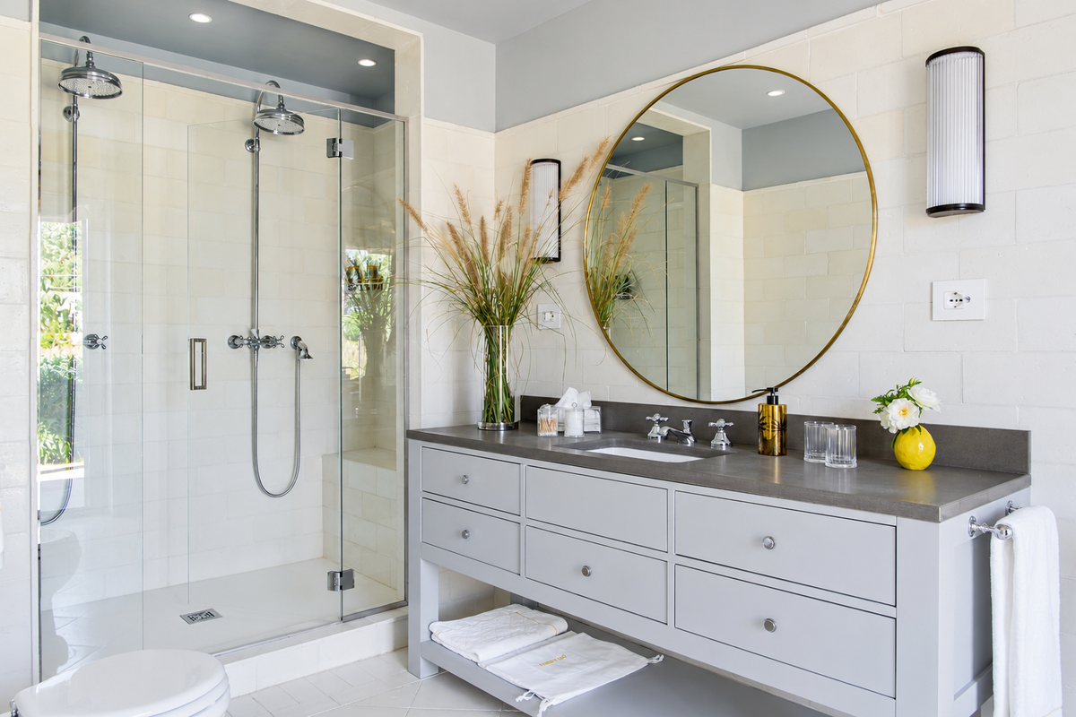 Bathroom with a walk-in shower and a round brass mirror