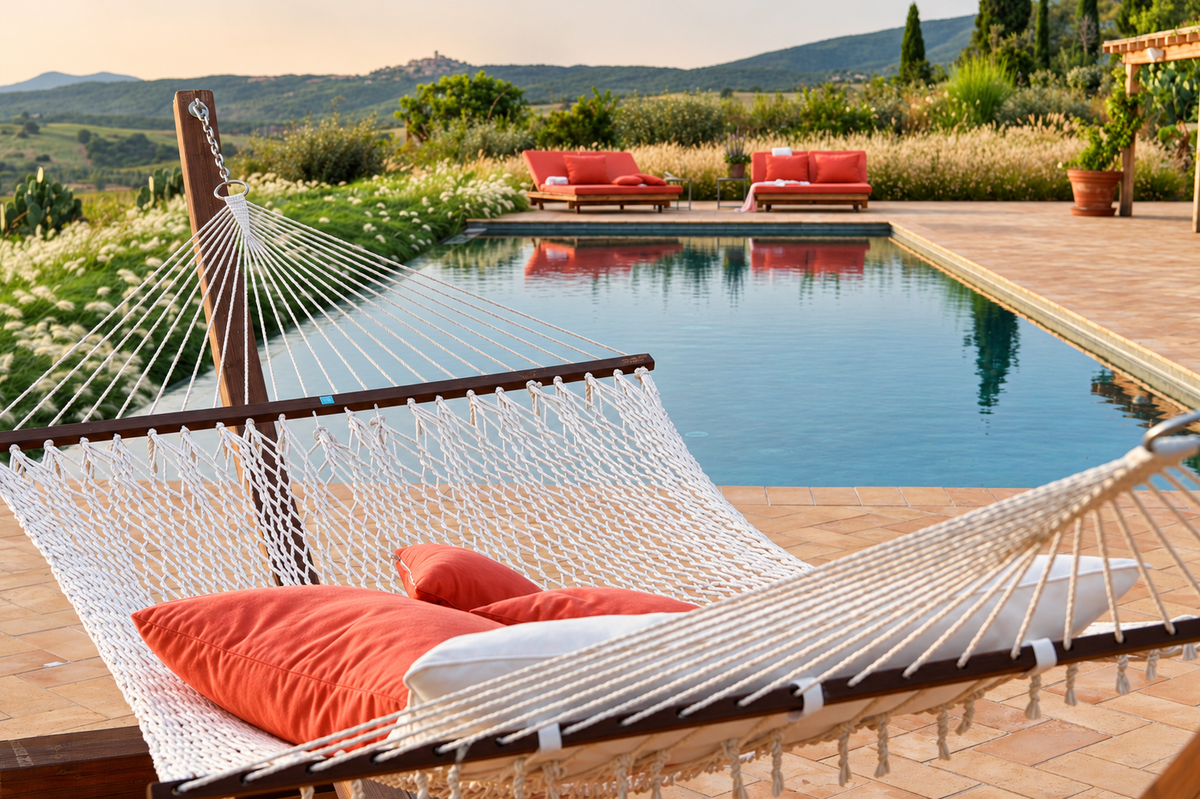 Hammock with orange cushions by the pool, a hilltop village in the distance