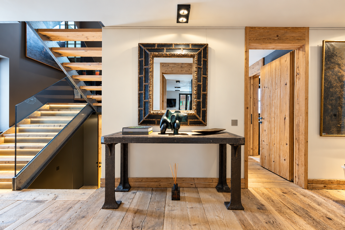Entrance hall with a lit staircase, a console and a mirror