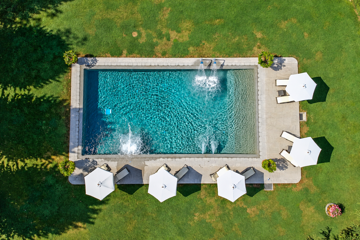 The pool from above, with fountain jets and white parasols on the lawn