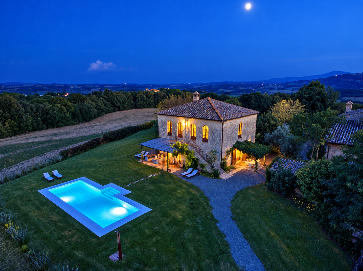 Aerial view of the villa and lit pool at night