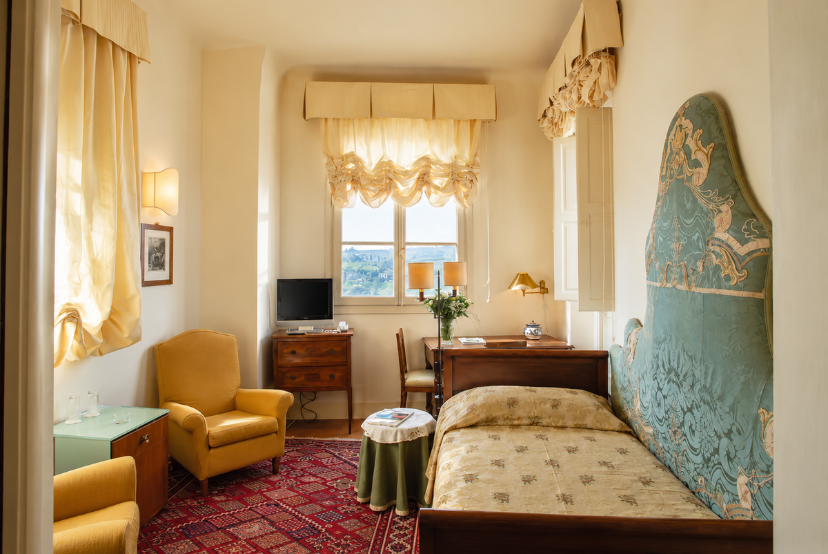 Bedroom with a green carved headboard and armchairs