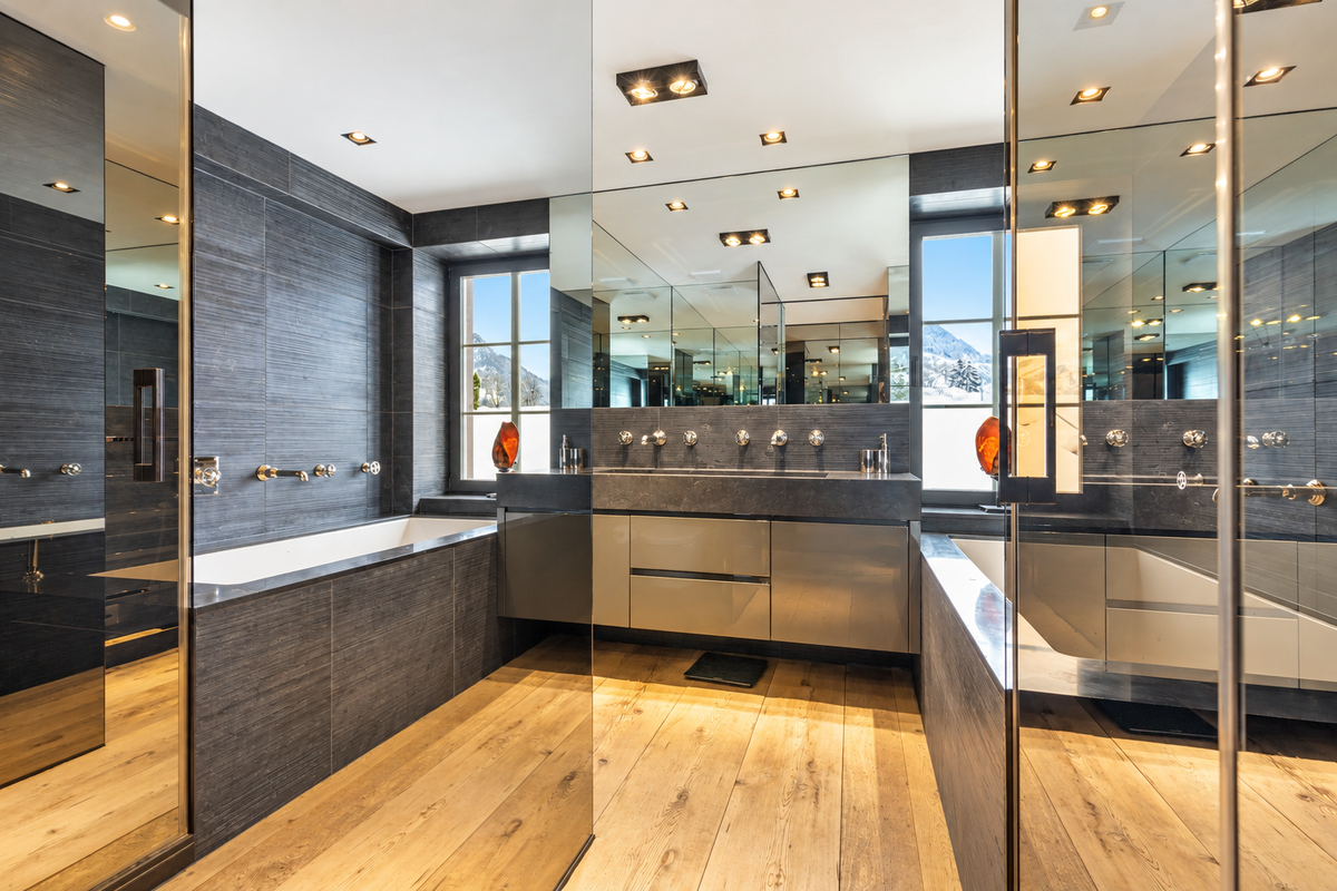 Bathroom with mirrored walls, a bath and a double basin
