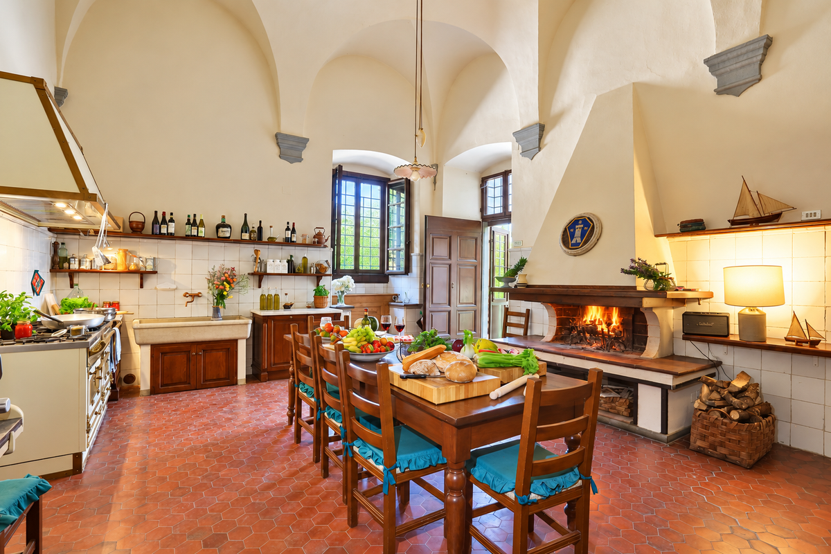 Vaulted kitchen with a lit fireplace and a long wooden table