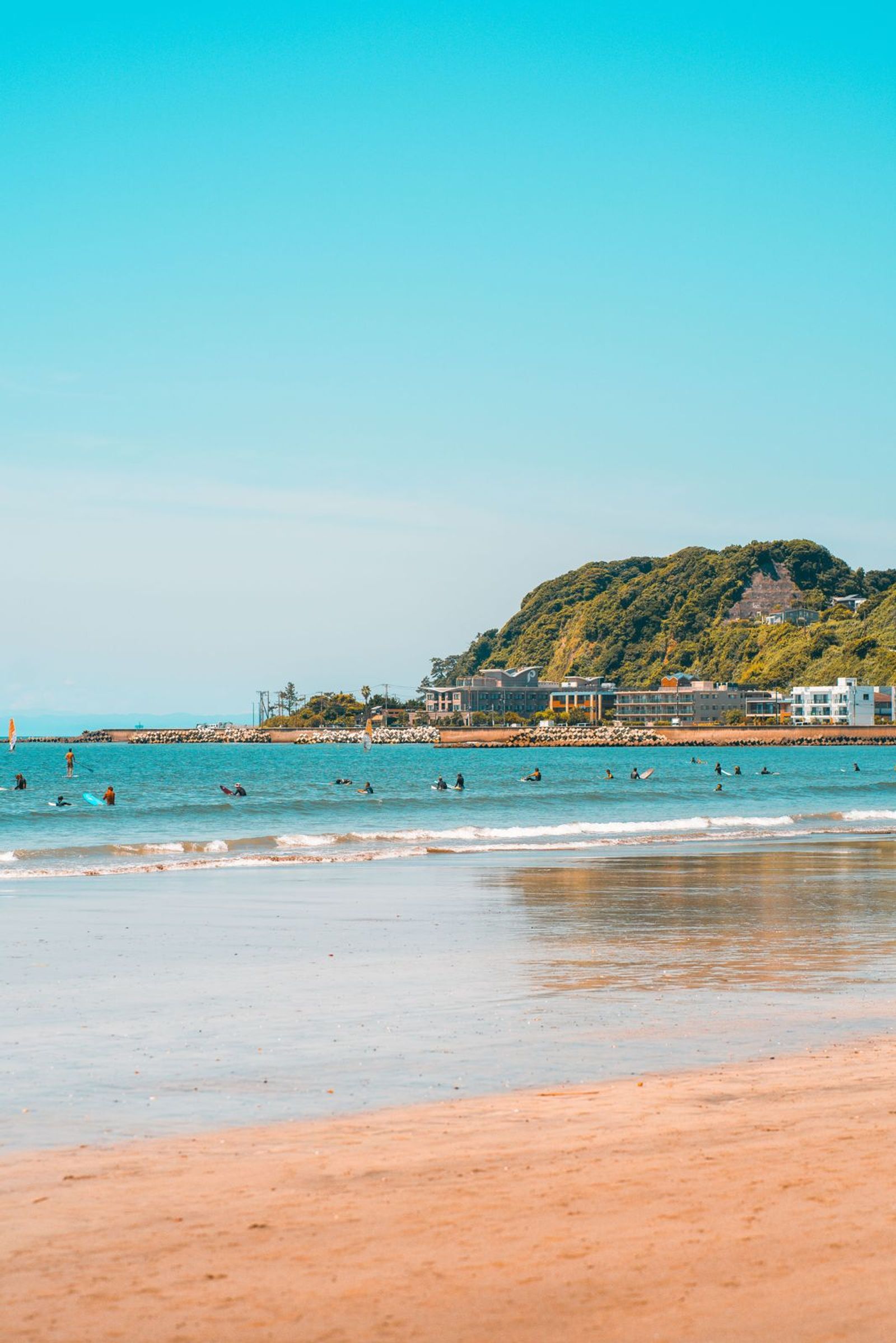 Plage de Shōnan avec surfeurs et colline verdoyante
