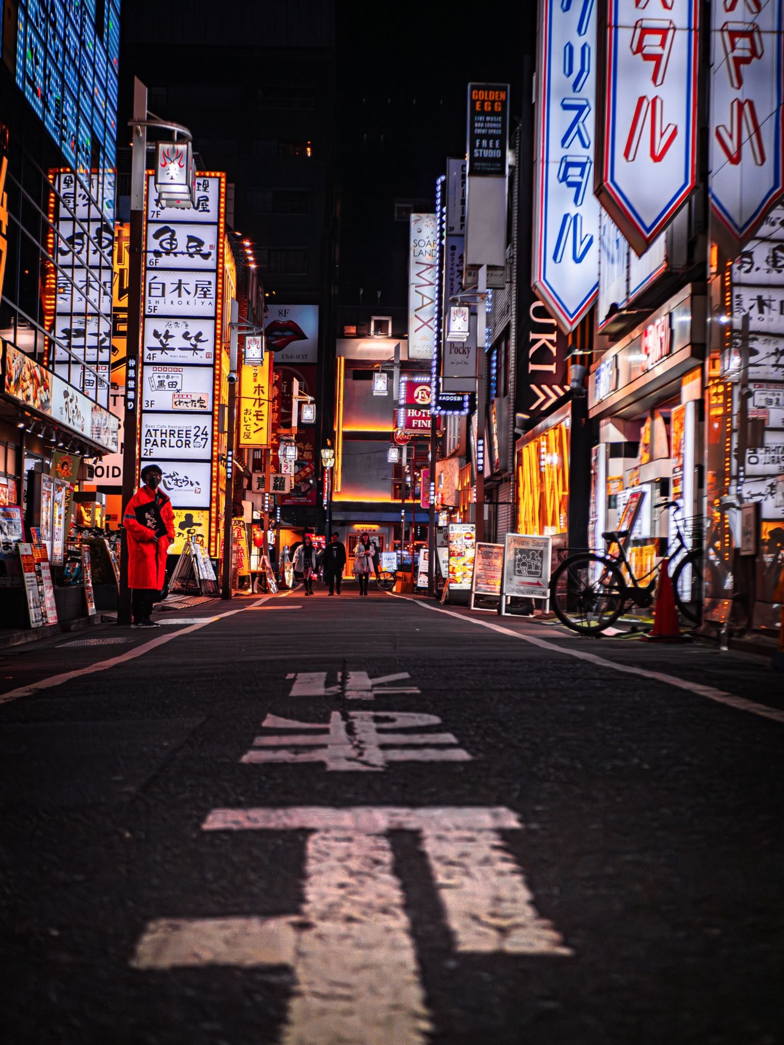 Rue de Shinjuku illuminée par les enseignes à la nuit tombée.