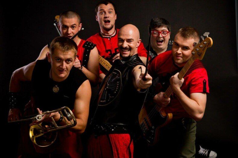 Учасники гурту «ГАЙДАМАКИ» з музичними інструментами на темному тлі.