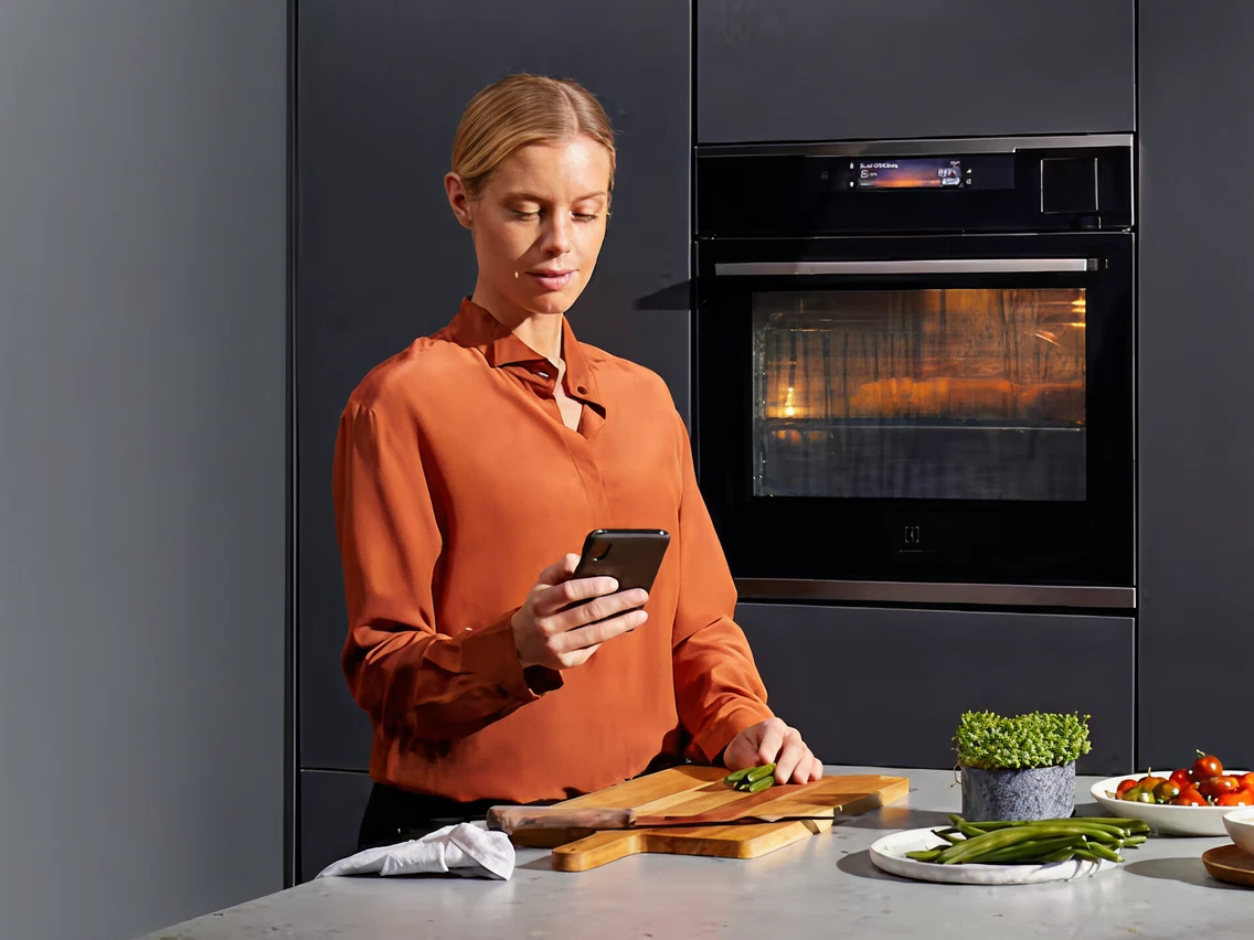 Women looks at her phone while cooking food