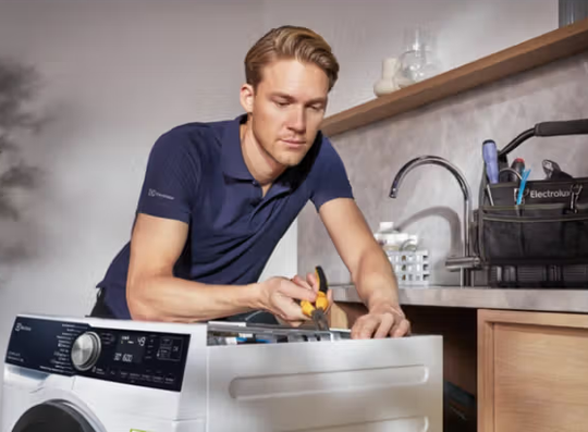 Electrolux servicetekniker reparerer tørretumbler hos kunde i hjemmet