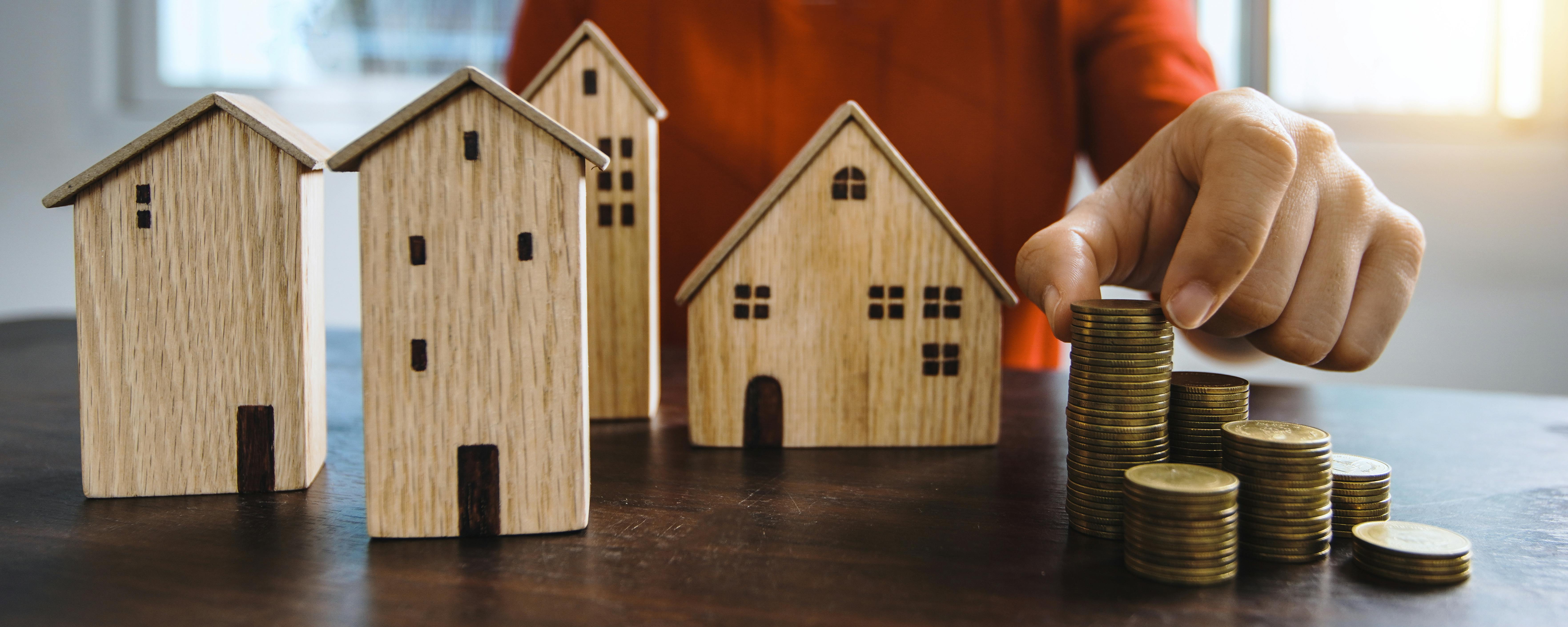 Image of a man stacking coins and models of rental houses and appartments