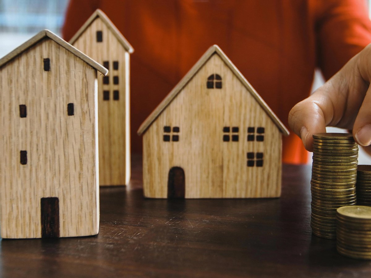 Image of a man stacking coins and models of rental houses and appartments