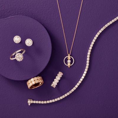 Assortment of gold jewelry laid on a dark purple backdrop