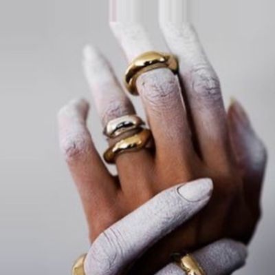 Hands that are painted white and wearing gold rings