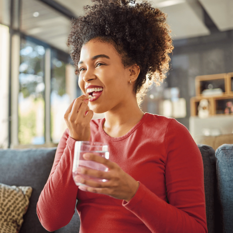 Image of Woman with a glass of water taking medication to treat sinusitis.