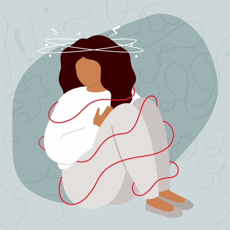 An illustration of a person, with a dejected body posture, sitting with swirls around their head and body to visualize the feeling of a panic attack.