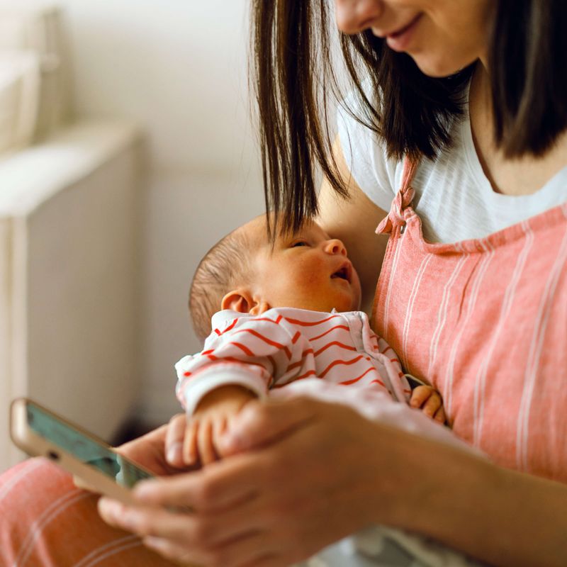 Mother Holding Baby, Completing Mental Health Assessment On Her Phone