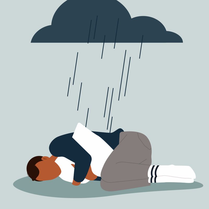 An illustration of a person laying down and holding onto a pillow under a rain cloud 