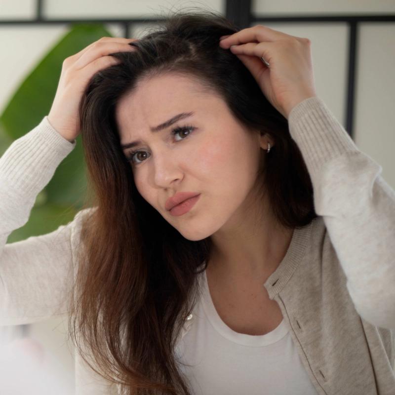 Image of Woman looking at her scalp for dandruff.