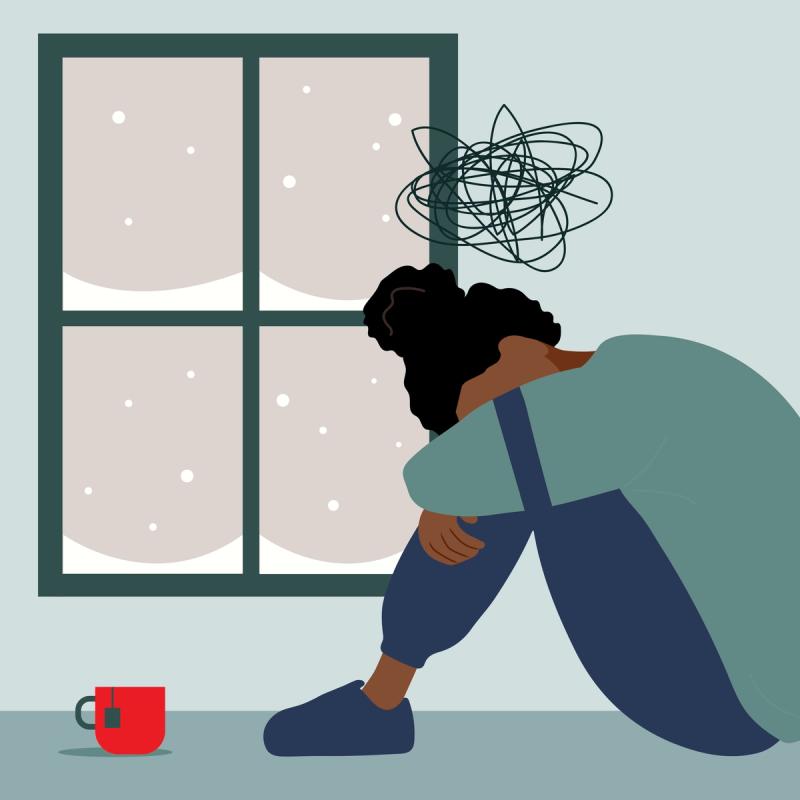 An illustration of a person, with a dejected body posture, sitting in front of a snow-covered window. A cup of tea is in the foreground.