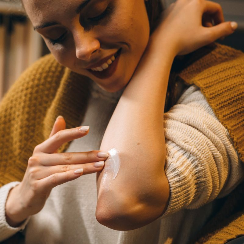 Image of Woman applying cream to elbow.