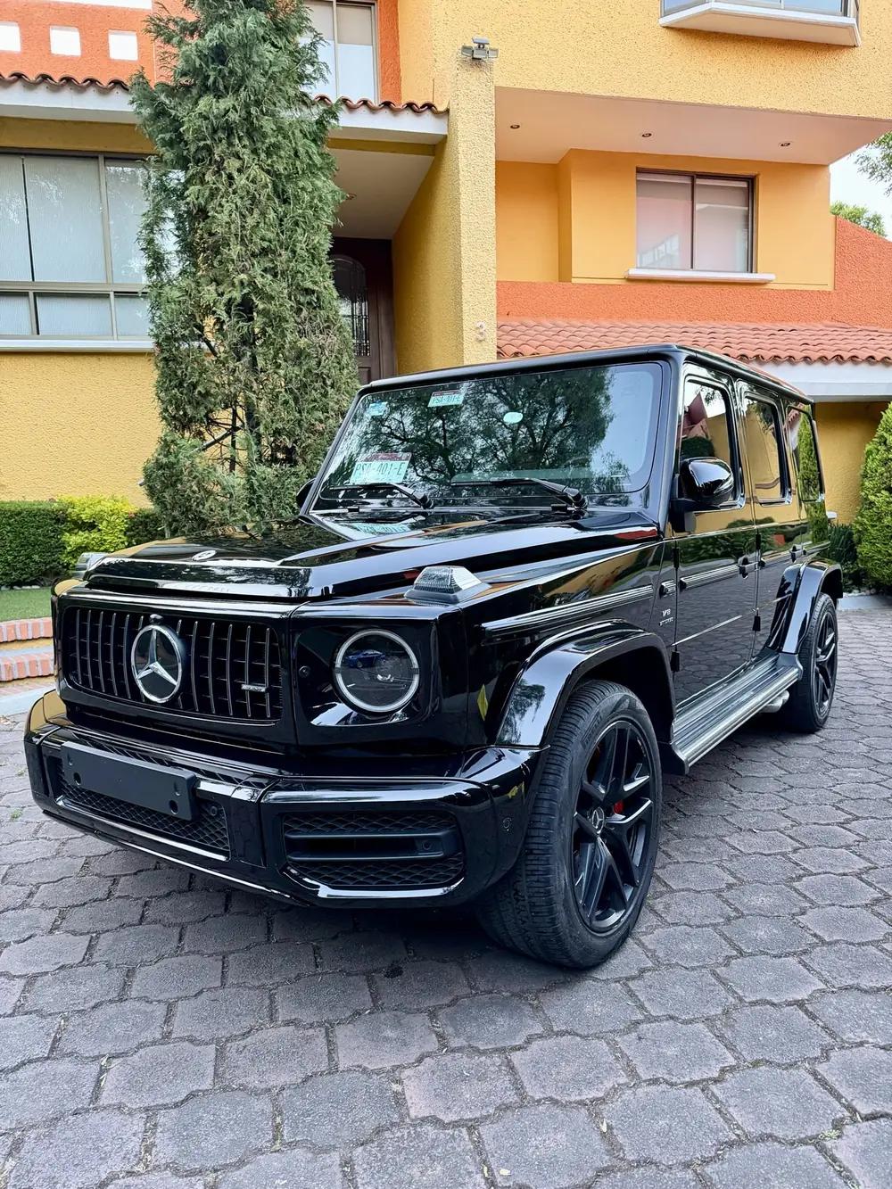 Mercedes-AMG G 63 negra con la pintura recién protegida, reflejando los árboles