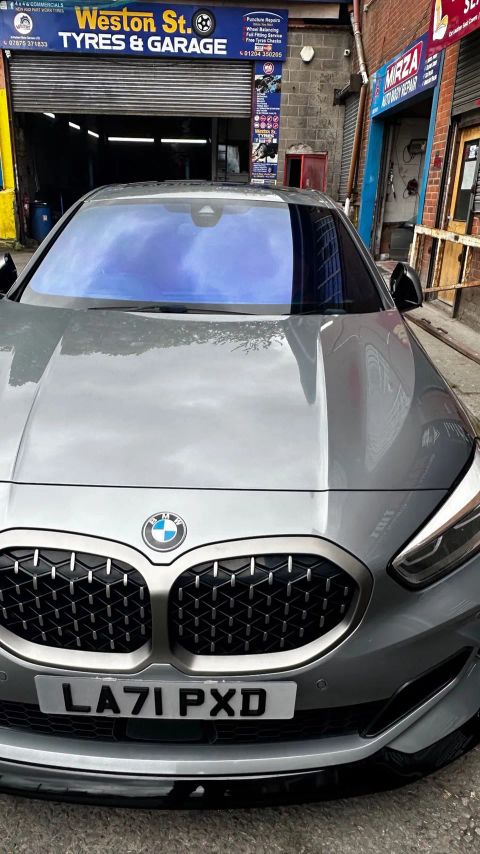 Grey BMW 1 Series with a blue colour-shift windscreen film on Weston Street, Bolton