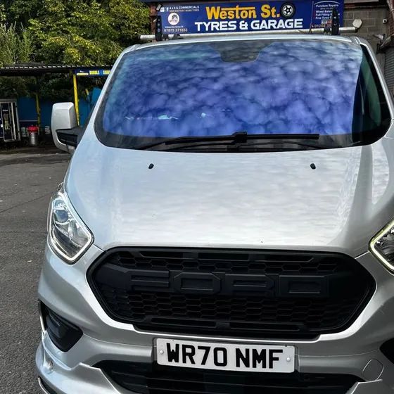 A silver Ford Transit Custom van with a chameleon windscreen