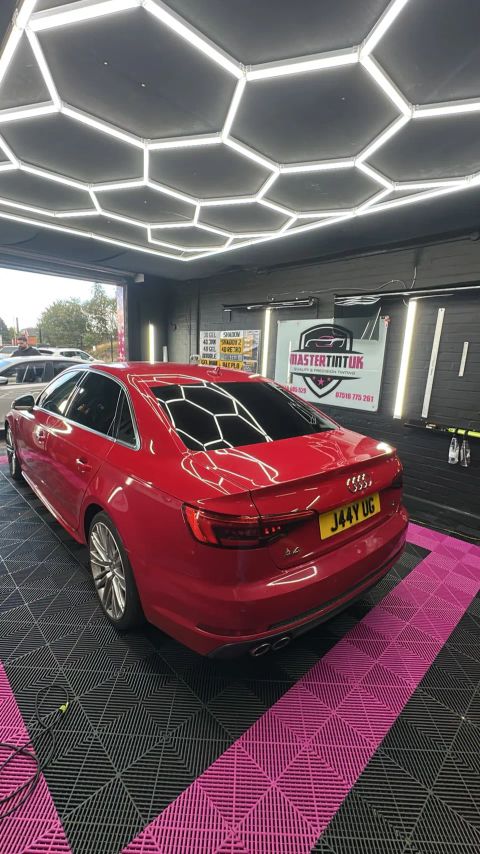 Red Audi A4 saloon with dark-tinted rear windows and rear screen in the MasterTint UK bay, Weston Street, Bolton