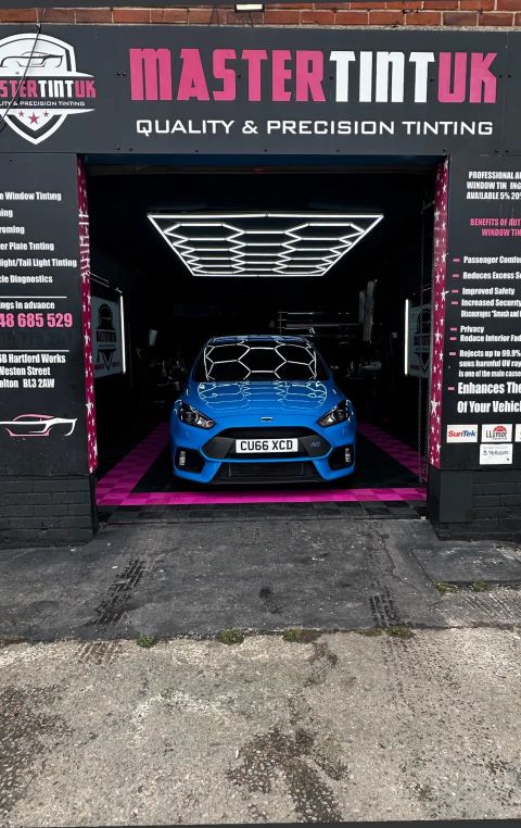 Blue Ford Focus RS in the bay at MasterTint UK, Weston Street, Bolton, seen from the street under the shop sign